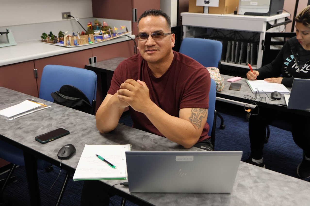 a man with sunglasses sitting in a classroom